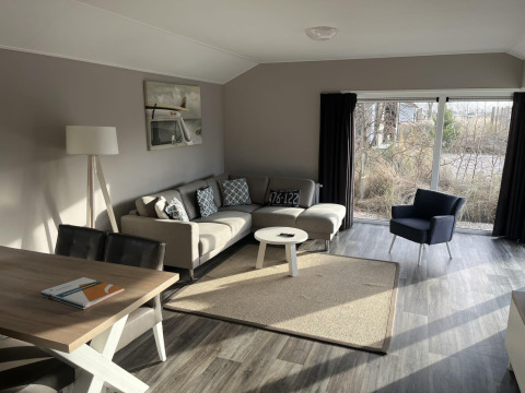 Helles, modernes Wohnzimmer in der Velthorst Lodge, Poort van Zeeland, Niederlande mit großen Fenstern.
