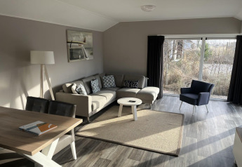 Luminoso soggiorno moderno nella lodge Velthorst a Poort van Zeeland, Paesi Bassi, con ampie finestre.