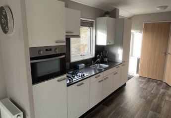 Cocina moderna blanca en una cabaña Velthorst en Poort van Zeeland, Países Bajos, con horno y estufa.