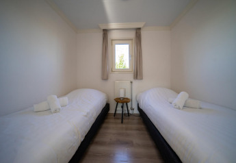 Camera con due letti singoli, piccolo tavolo e finestra presso la Velthorst lodge, Poort van Zeeland, Paesi Bassi.