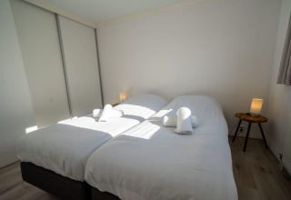 Dormitorio con dos camas individuales y sábanas blancas en la cabaña Velthorst de Poort van Zeeland, Países Bajos.