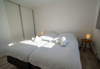 Schlafzimmer mit zwei Einzelbetten und weißen Bettbezügen in der Velthorst-Lodge, Poort van Zeeland.