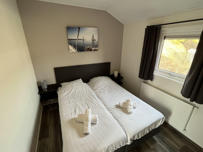 Dormitorio con dos camas individuales, ventana con cortinas y cuadro de veleros en la pared en Velthorst lodge.