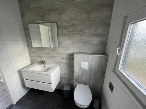Baño moderno con inodoro suspendido, lavabo, espejo y ventana en Velthorst, Poort van Zeeland.