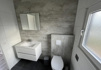 Bagno moderno con wc sospeso, lavabo, specchio e finestra al Velthorst, Poort van Zeeland.