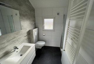 Baño moderno en la cabaña Velthorst de Poort van Zeeland, Países Bajos, con azulejos blancos y diseño limpio.