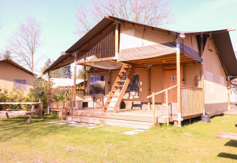 Tienda safari Ranger en Camping Vossenberg, Países Bajos, con terraza de madera y bancos de picnic.