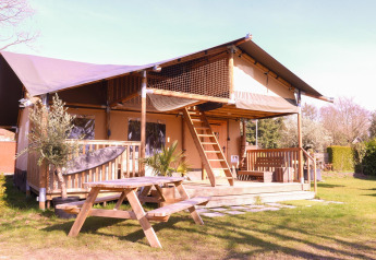 Tienda safari Ranger en Camping Vossenberg, Países Bajos, con terraza de madera y mesa de picnic exterior.