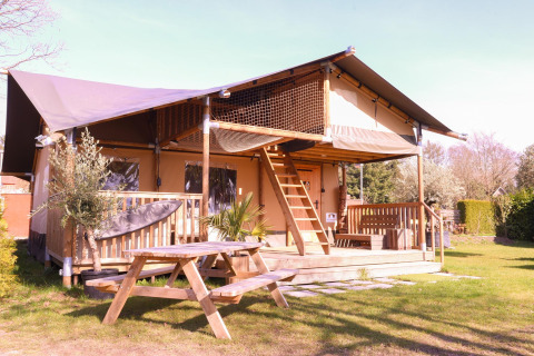 Safari tent Ranger at Camping Vossenberg in the Netherlands, with wooden deck and picnic bench in grassy area.