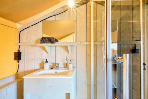 Badkamer in Safari tent Ranger bij Camping Vossenberg, Nederland, met wastafel, spiegel en douchecabine.