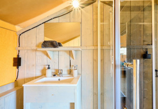 Badkamer in Safari tent Ranger bij Camping Vossenberg, Nederland, met wastafel, spiegel en douchecabine.