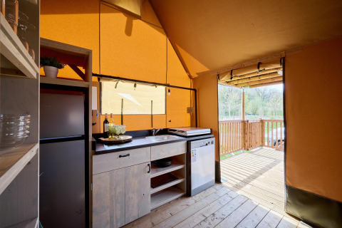 Vista interior de la tienda Safari Ranger en Camping Vossenberg, Países Bajos, con cocina y terraza exterior.