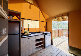 Vista interior de la tienda Safari Ranger en Camping Vossenberg, Países Bajos, con cocina y terraza exterior.