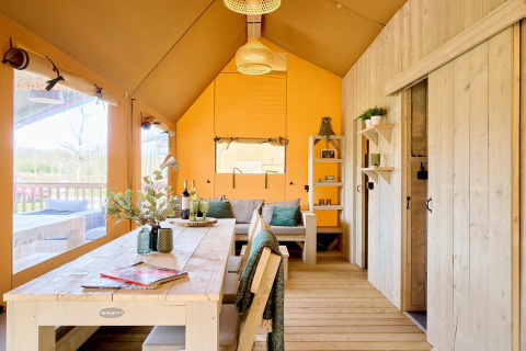 Interior de una espaciosa tienda safari en Camping Vossenberg, Países Bajos, con muebles de madera.