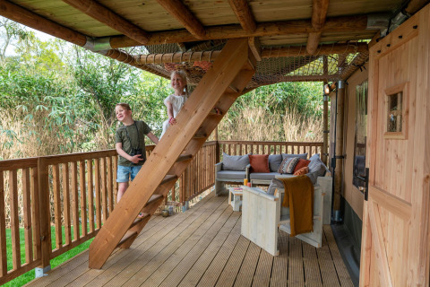 Twee kinderen spelen op een houten trap bij een safaritent op Camping Vossenberg in Nederland.