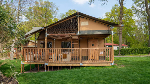Safari tent Ranger at Camping Vossenberg in the Netherlands, featuring a wooden deck among green trees.