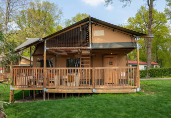 Safari tent Ranger at Camping Vossenberg in the Netherlands, featuring a wooden deck among green trees.
