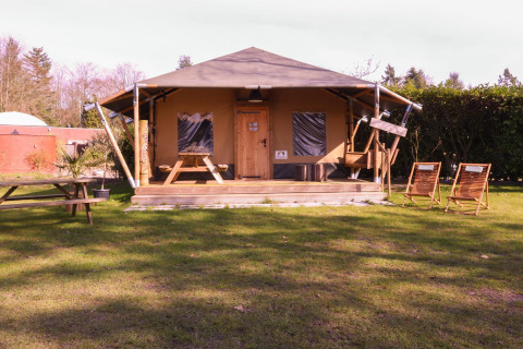 Tenda safari Cottage al Camping Vossenberg nei Paesi Bassi con sedie a sdraio e tavoli da picnic davanti.