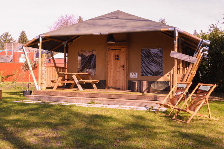Safari tent Cottage at Camping Vossenberg, Netherlands, with wooden deck, picnic table, and chairs.