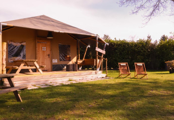 Safari-Zelt Cottage auf dem Campingplatz Vossenberg in den Niederlanden mit Holzmöbeln und Garten.
