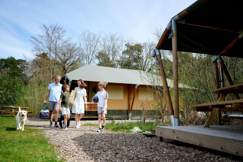 Family with dog enjoying a summer day outside the Safari tent Cottage at Camping Vossenberg in the Netherlands.