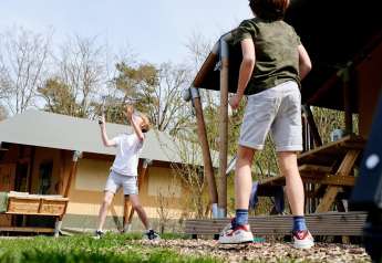 Dos niños juegan bádminton frente a una tienda safari en Camping Vossenberg, Países Bajos.