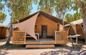 Tente safari chez Villatent Outback avec terrasse en bois, hamac et grands arbres pour l’ombre.