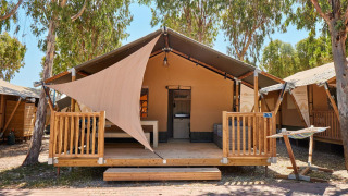Tente safari chez Villatent Outback avec terrasse en bois, hamac et grands arbres pour l’ombre.