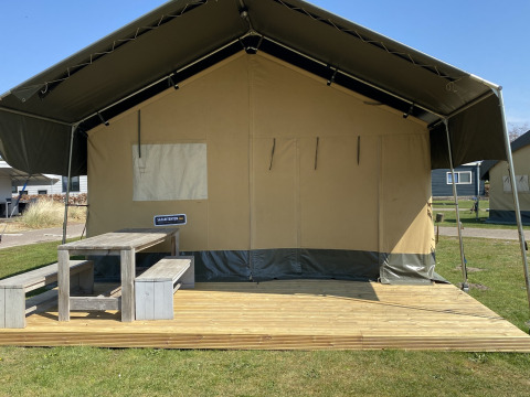 Tienda safari en Holiday Park Duinhoeve, Países Bajos, con terraza de madera y banco de picnic al aire libre.