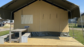 Safaritent bij Holiday Park Duinhoeve in Nederland met houten veranda en picknickbank buiten.