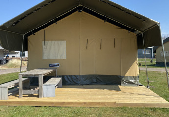 Safari-Zelt im Ferienpark Duinhoeve in den Niederlanden mit Holzterrasse und Picknicktisch draußen.
