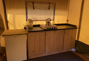 Cucina di tenda safari al Holiday Park Duinhoeve, Paesi Bassi, con fornello, bollitore e frigorifero.