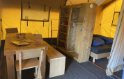 Interno di una tenda safari all'Holiday Park Duinhoeve nei Paesi Bassi con mobili in legno e letto.