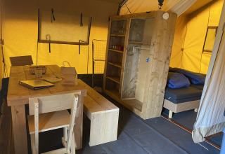 Interno di una tenda safari all'Holiday Park Duinhoeve nei Paesi Bassi con mobili in legno e letto.