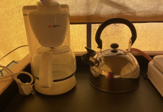 Koffiezet en waterketel op het aanrecht in safaritent in Holiday Park Duinhoeve, Nederland, bij ochtendlicht.