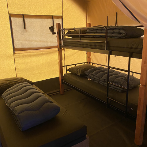 Binnenkant van een safaritent in Holiday Park Duinhoeve in Nederland met stapelbed en enkel bed.