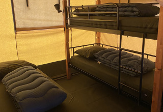 Interior de una tienda safari en Holiday Park Duinhoeve, Países Bajos, con litera y cama individual.