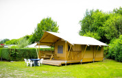 Tienda safari Glamping Deluxe en Holiday Park Duinhoeve, Países Bajos, rodeada de césped y mobiliario exterior.