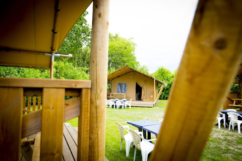 Vista de una tienda safari Glamping Deluxe tipo 1 en Holiday Park Duinhoeve, Países Bajos, con asientos exteriores.