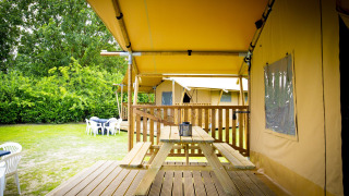 Tienda safari Glamping Deluxe tipo 1 en Holiday Park Duinhoeve, Países Bajos, con terraza y mesa de picnic.