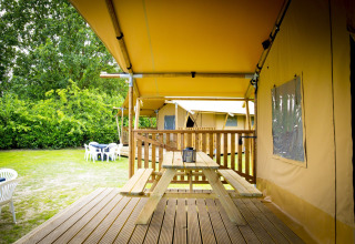 Tienda safari Glamping Deluxe tipo 1 en Holiday Park Duinhoeve, Países Bajos, con terraza y mesa de picnic.