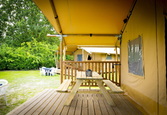 Glamping Deluxe type 1 safaritent bij Holiday Park Duinhoeve in Nederland, met houten veranda en picknicktafel.