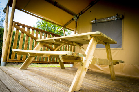 Mesa de picnic de madera bajo una tienda safari, Glamping Deluxe tipo 1, Holiday Park Duinhoeve, Países Bajos.