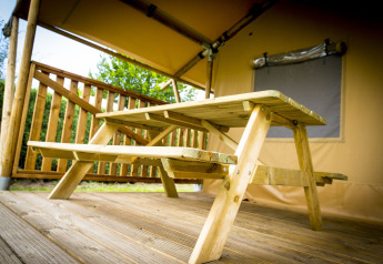 Mesa de picnic de madera bajo una tienda safari, Glamping Deluxe tipo 1, Holiday Park Duinhoeve, Países Bajos.