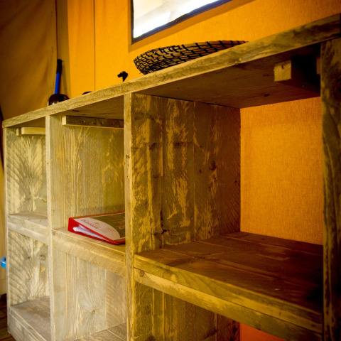 Estantería de madera dentro de una tienda safari Glamping Deluxe en Holiday Park Duinhoeve, Países Bajos.