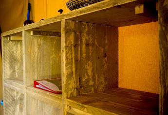 Estantería de madera dentro de una tienda safari Glamping Deluxe en Holiday Park Duinhoeve, Países Bajos.
