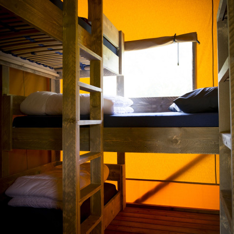 Interior de la tienda safari Glamping Deluxe tipo 1 con literas en Holiday Park Duinhoeve, Países Bajos.