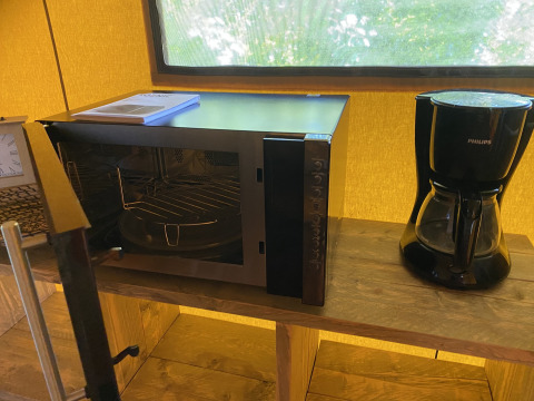 Microondas y cafetera sobre una estantería de madera en una tienda glamping en Holiday Park Duinhoeve.