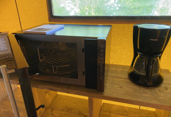 Microondas y cafetera sobre una estantería de madera en una tienda glamping en Holiday Park Duinhoeve.