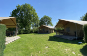 Tres tiendas safari Glamping Deluxe tipo 1 en Holiday Park Duinhoeve, Países Bajos, sobre césped verde.